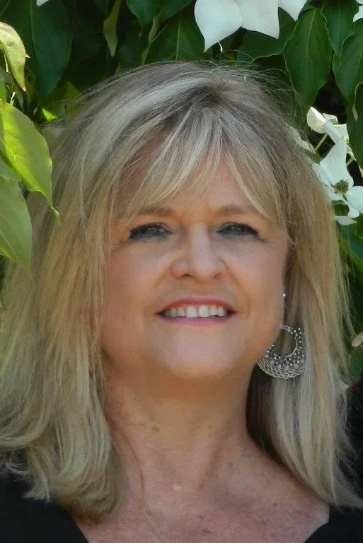 A woman with long blonde hair and silver earrings.