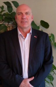 A man in a suit standing next to a plant.