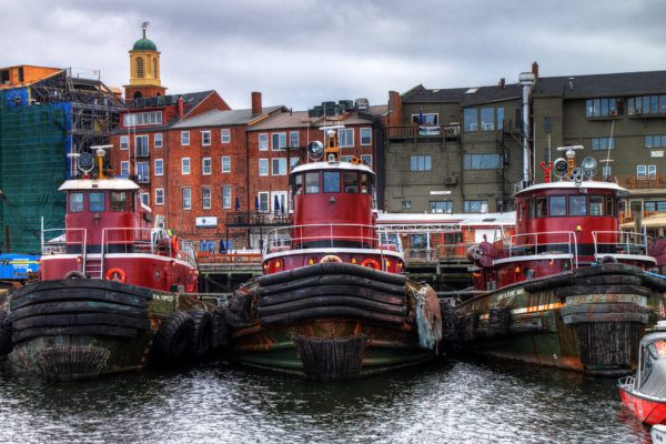 Three red tugboats in a body of water
