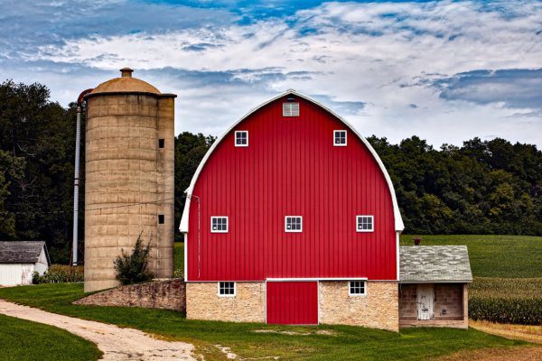 A red barn with two silos in the background.