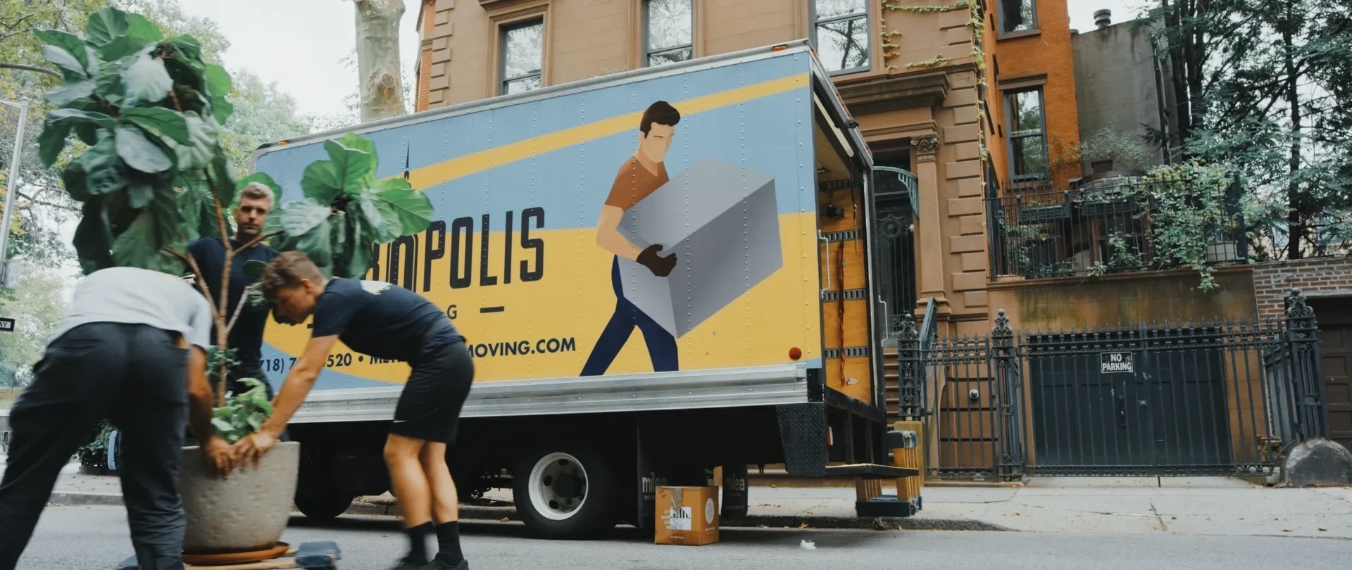 A moving truck with a man carrying boxes on the back.