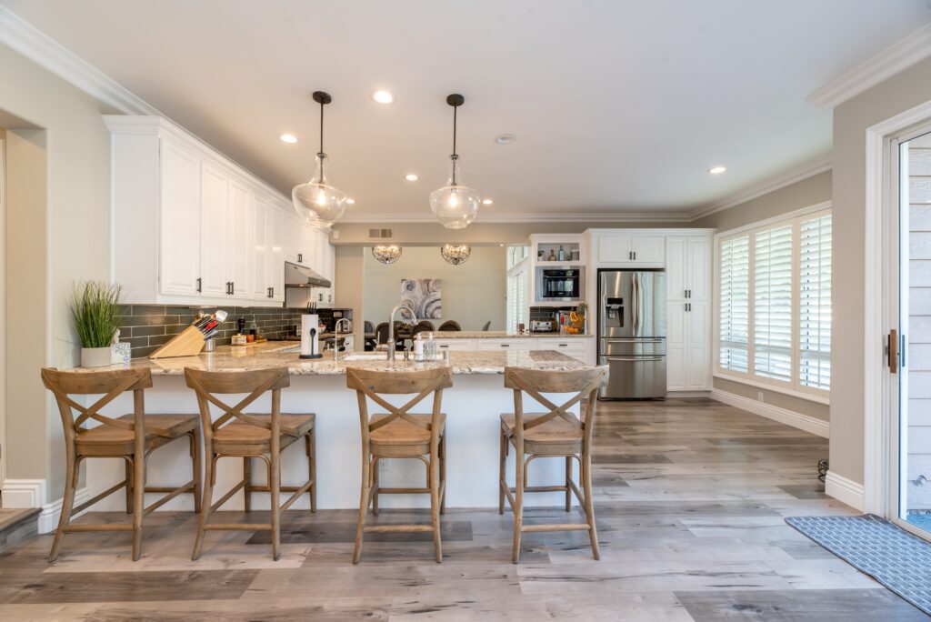 A kitchen with white cabinets and wooden floors.