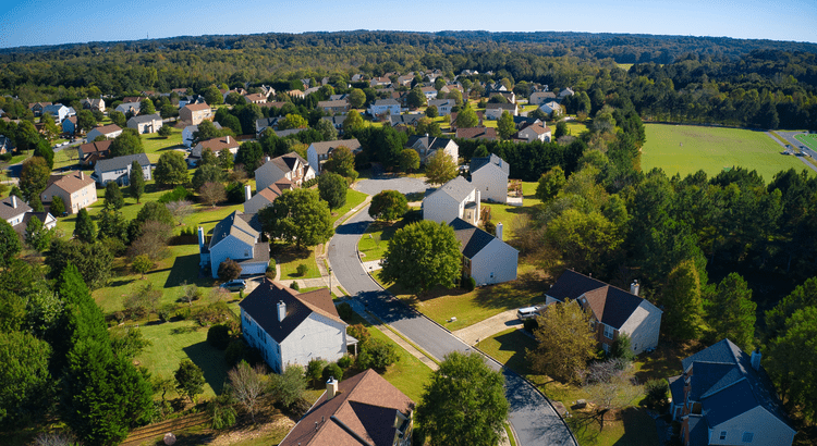 A serene suburban neighborhood with houses and greenery on a sunny day.