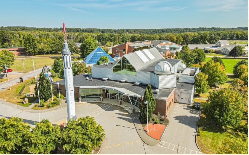 Modern church with a tall white steeple in a green suburban area.