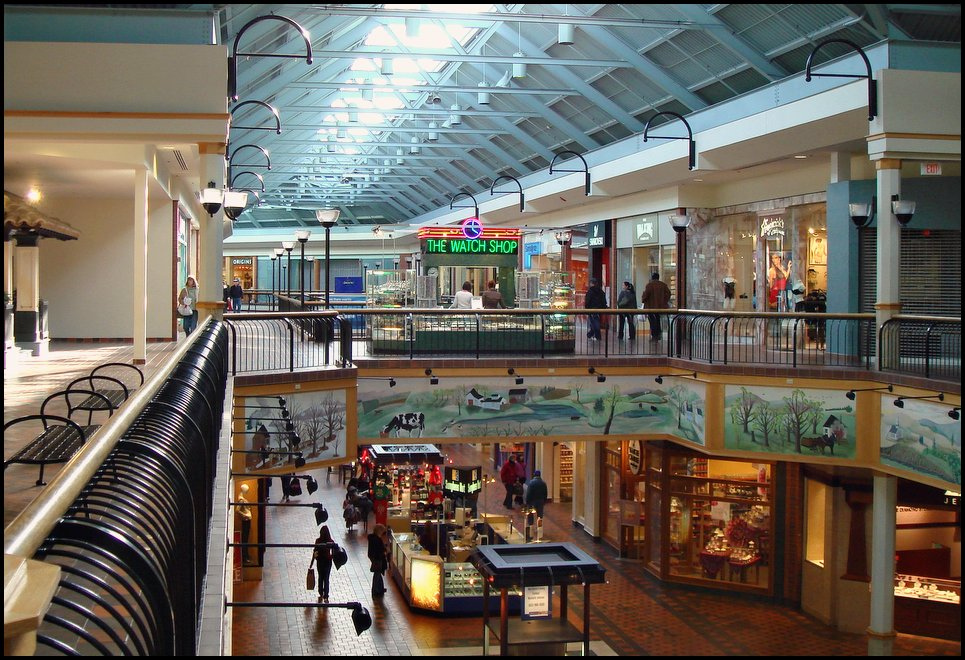 Interior view of a spacious shopping mall with multiple stores and shoppers.
