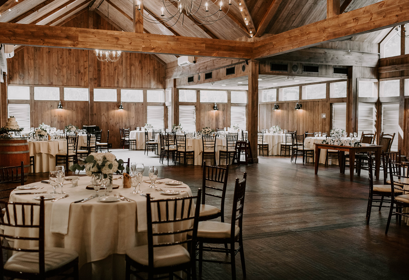 Cozy rustic banquet hall with wooden beams and elegant table settings.
