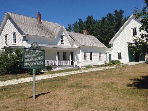 Historic white wooden house with a green informational sign in front.