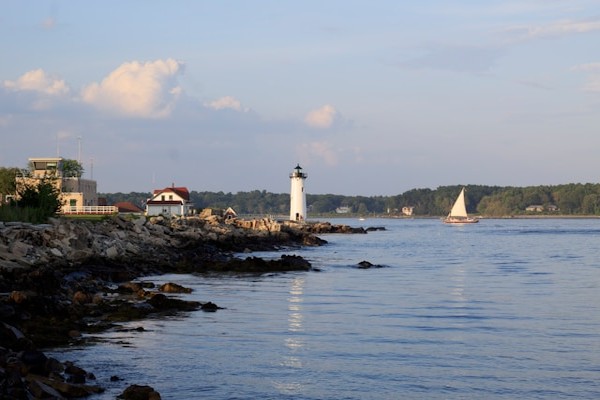 Portsmouth Harbor Lighthouse in New Castle, NH with sailboat on the Piscataqua River